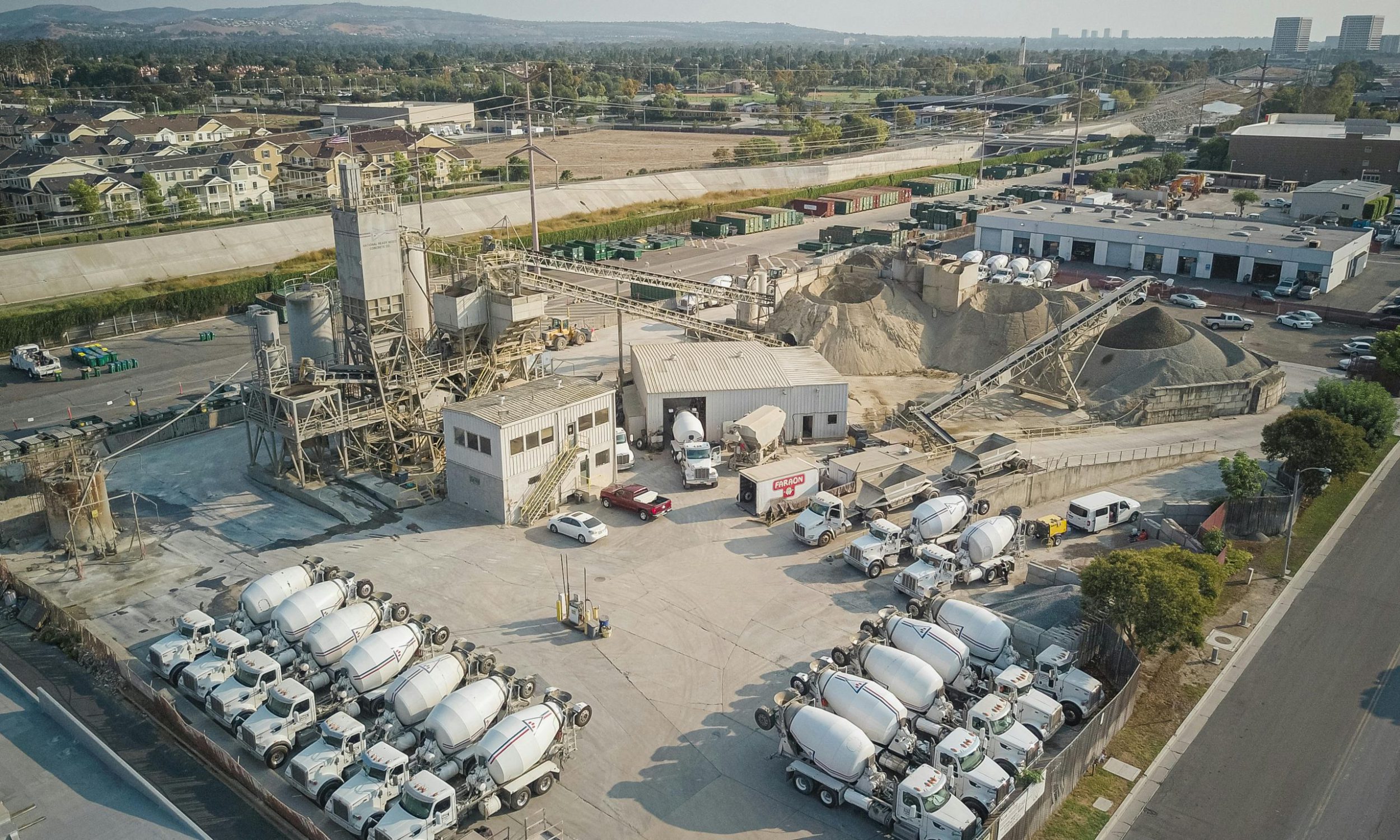 Aerial shot of a bustling cement manufacturing plant with mixer trucks and industrial equipment.